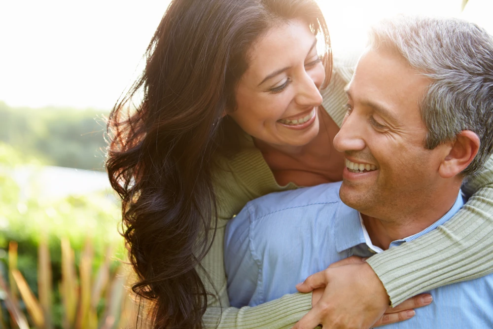 Smiling couple embracing outdoors after hormone replacement.