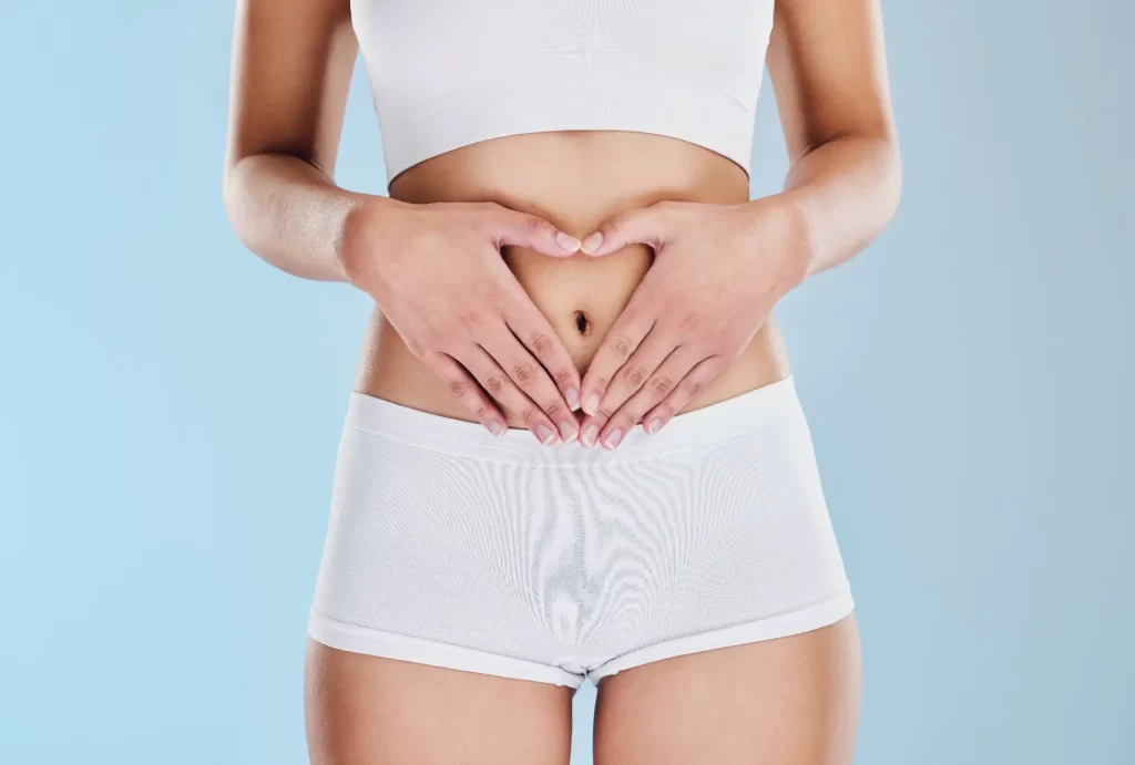 Person forming heart shape with hands over abdomen